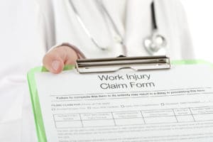 Doctor holding a work injury claim form on a clipboard