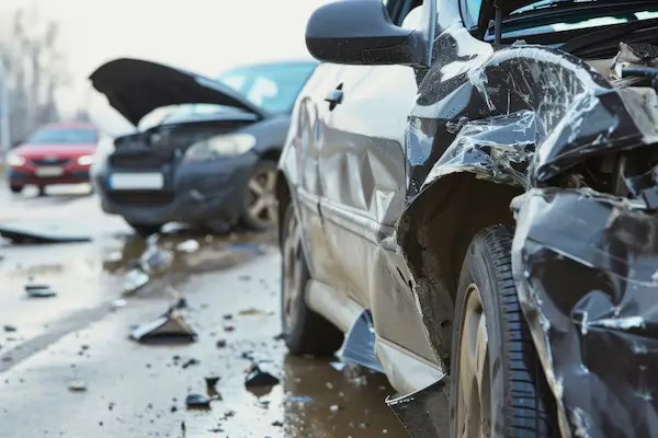 Two damaged cars stopped in the road after collision.