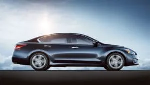 A dark blue sedan is parked on a flat surface.