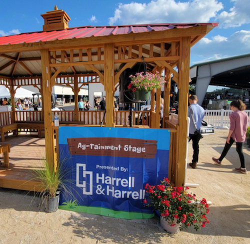 People walk past Ag-Tainment Stage gazebo with banner.