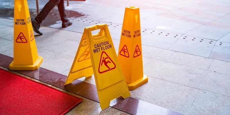 Three yellow wet floor signs near a red carpet.