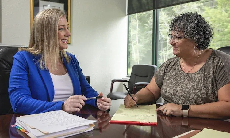 Two women sit at a table, smiling and talking.