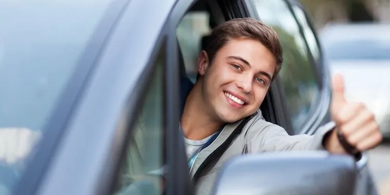 A young man smiles and gives a thumbs-up.