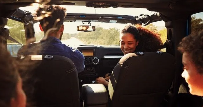 Woman smiles in passenger seat as kids ride along.