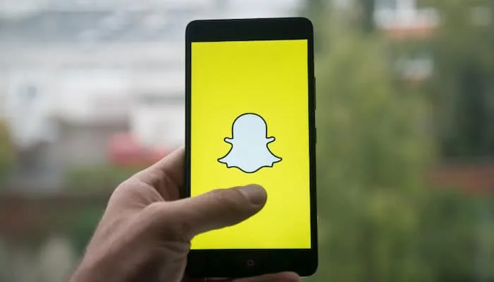 Hand holding phone with Snapchat logo on screen.