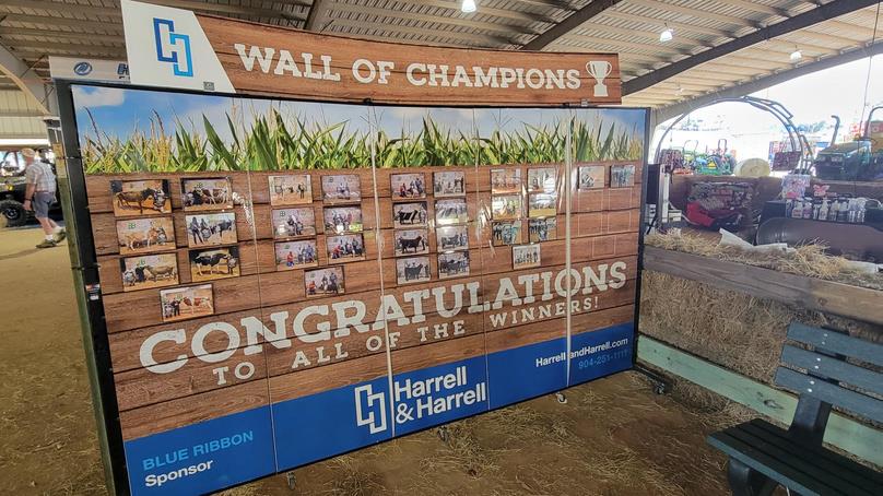 Wall of Champions display board shows winner photos and logo.