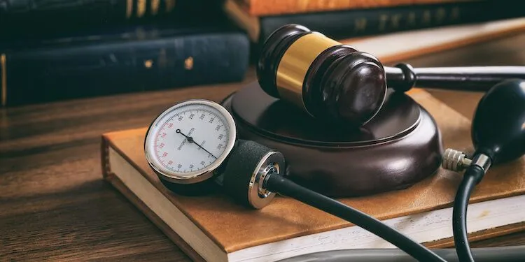 Gavel on a legal book beside a blood pressure monitor.