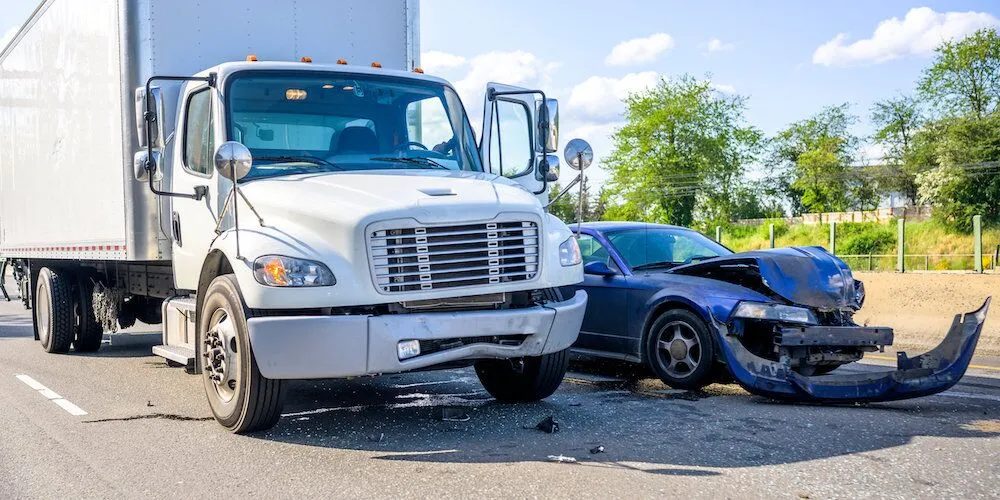 Semi-truck and car collide on a road.
