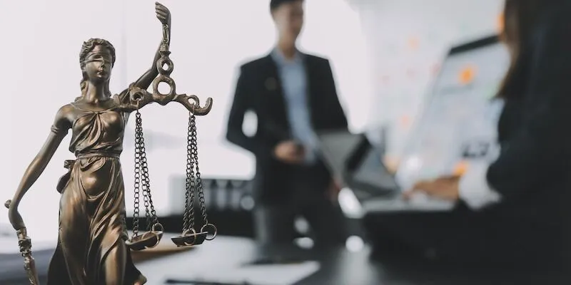 Lady Justice statue in front of two people working.