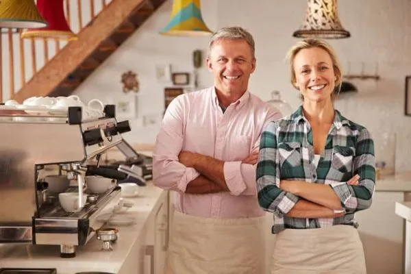 Two people in aprons stand with arms crossed.