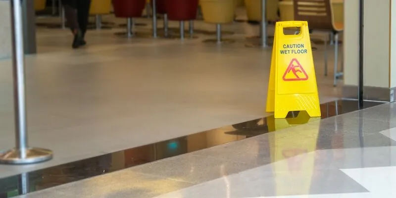 Caution Wet Floor sign stands on shiny floor.