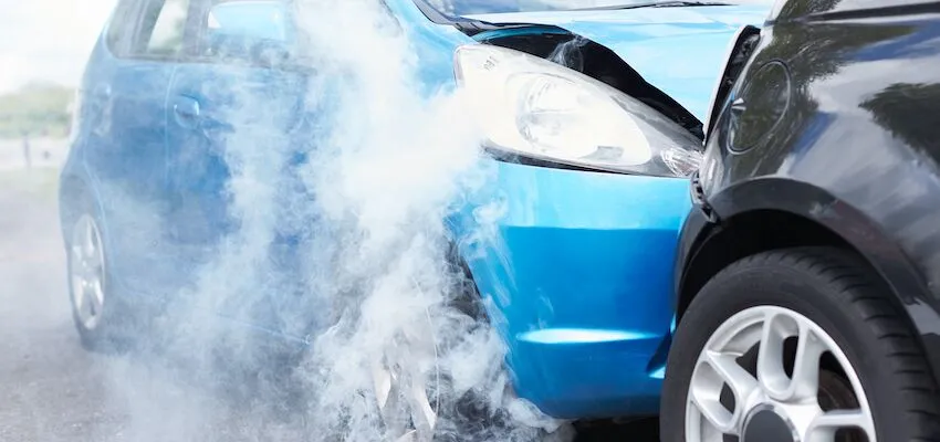 Blue car crashes into black car, white smoke rises.