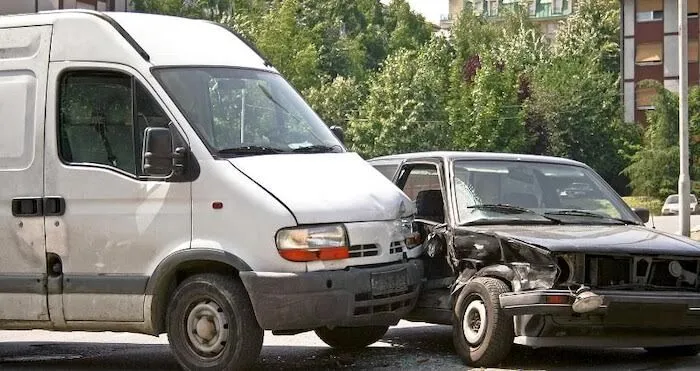 A white van and a black car collide at intersection.