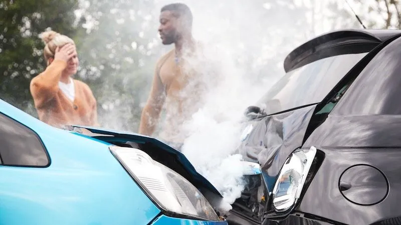 Two people stand by cars after a collision.