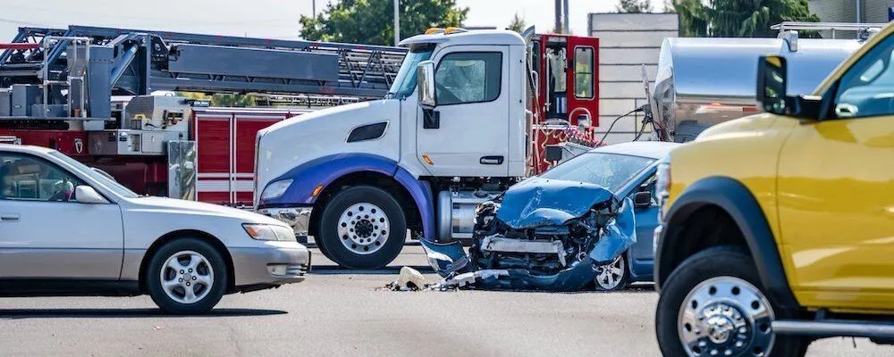 Blue car with front-end damage sits in intersection.