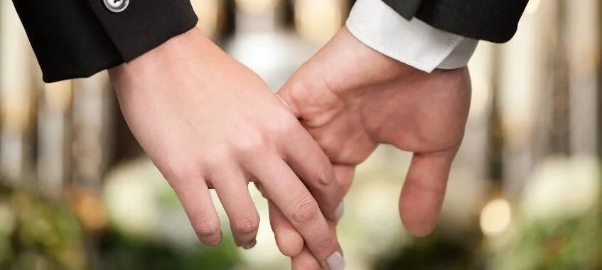 Two people holding hands in formal attire.