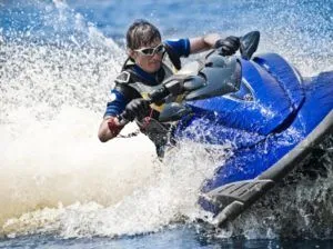 Person in sunglasses and life vest rides blue jet ski.