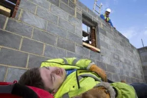 Injured worker on ground as coworker looks down.