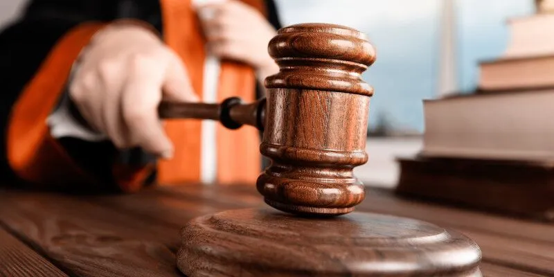 Judge's hand holding a wooden gavel above sound block.