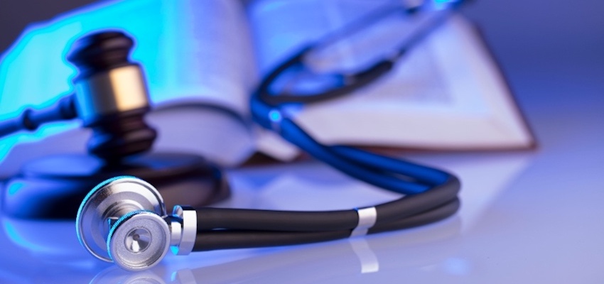 Stethoscope beside judge’s gavel and open book.