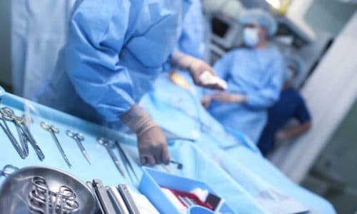 Surgeons in blue scrubs perform an operation.