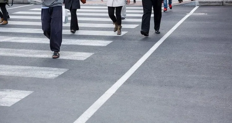People crossing the street, only legs and feet visible.
