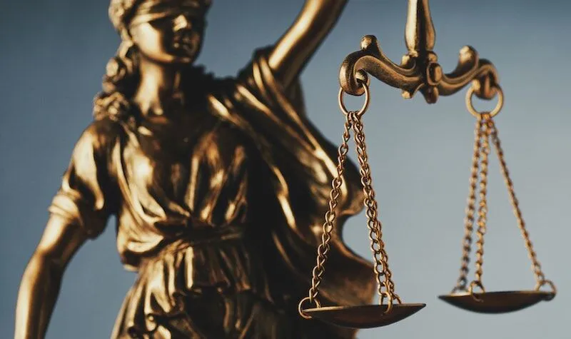 Lady Justice statue raises balanced scales, blindfolded.