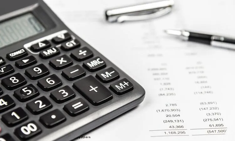 Calculator, pen, and financial documents on a white desk.
