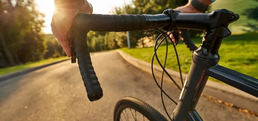 Person’s hand gripping bicycle handlebars.
