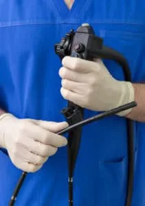 Person in blue scrubs holds an endoscope.