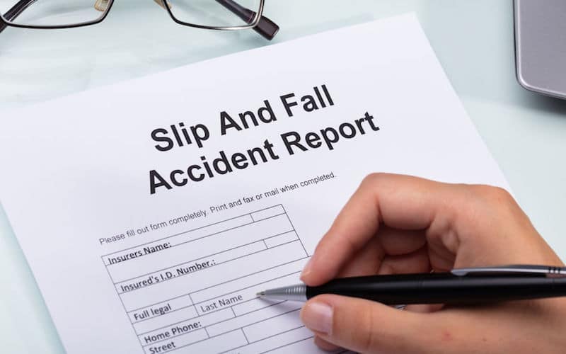 Hand filling out Slip And Fall Accident Report form.