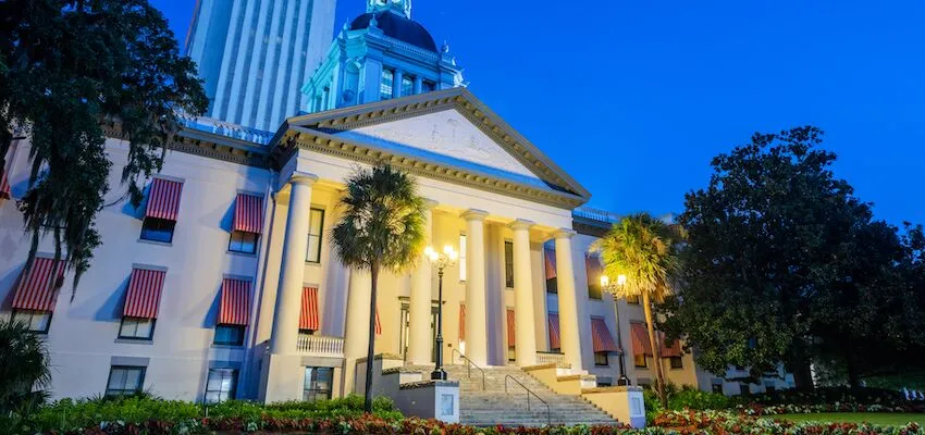 Historic building with columns and palm trees at twilight.