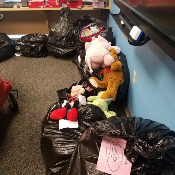 Garbage bags with plush toys stacked against a blue wall.