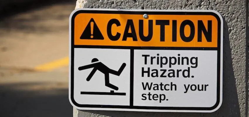 Warning sign shows person tripping over an obstacle.