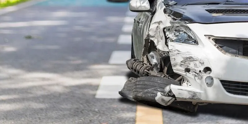 A white car with front right damage and bent wheel.