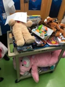Cart filled with toys including teddy bears and board games.