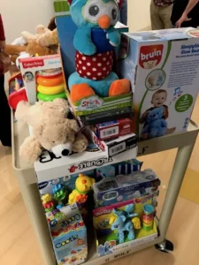 Cart holding plush owl, teddy bear, games, and toys.