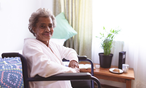 Elderly woman with short gray hair smiles in wheelchair.